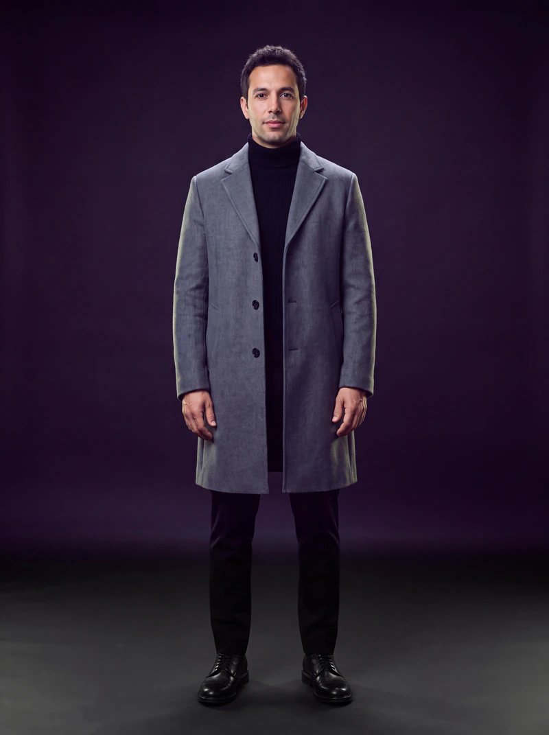 A man in a slate grey wool overcoat, seen from the front